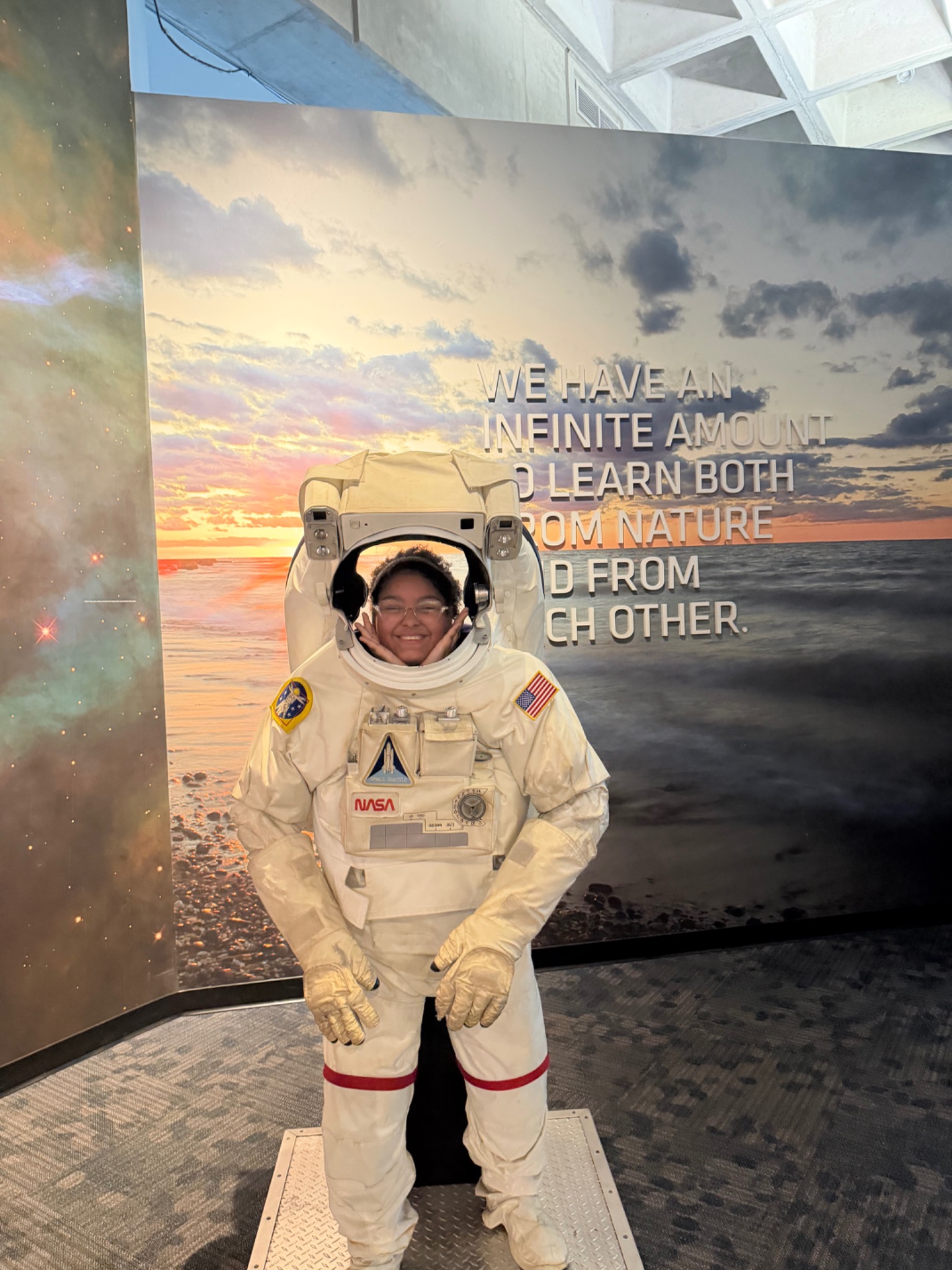 A student smiling inside an astronaut suit exhibit